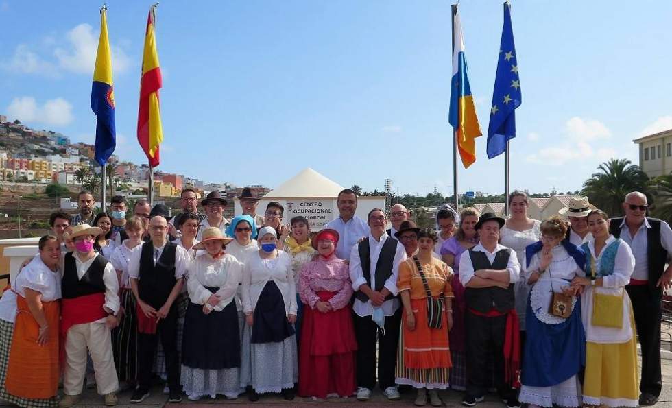 El alcalde, Pedro Rodríguez, junto a los usuarios y monitores del Centro Ocupacional Comarcal Santa María de Guía tras el izado de las banderas