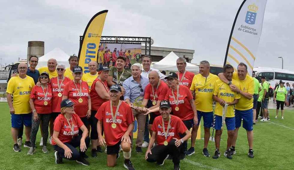 Los integrantes del equipo del Centro de Mayores de Gu&iacute;a, con camiseta roja, con el trofeo del II Torneo de F&uacute;tbol Caminando AlGolpito