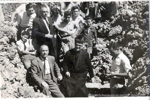 El párroco D, Manuel Alonso Luján, el comisario de excavaciones arqueológicas D.  Sebastián. Jiménez, el alcalde de Agaete, D. Pedro Esparza y niños de la villa, dentro del túmulo donde se encontró el sarcófago aborigen, Junio de 1957. (Historias y personajes de Agaete)