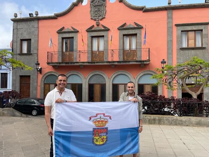 El alcalde Pedro Rodríguez junto a Manu Luján con la bandera del municipio frente a las Casas Consistoriales